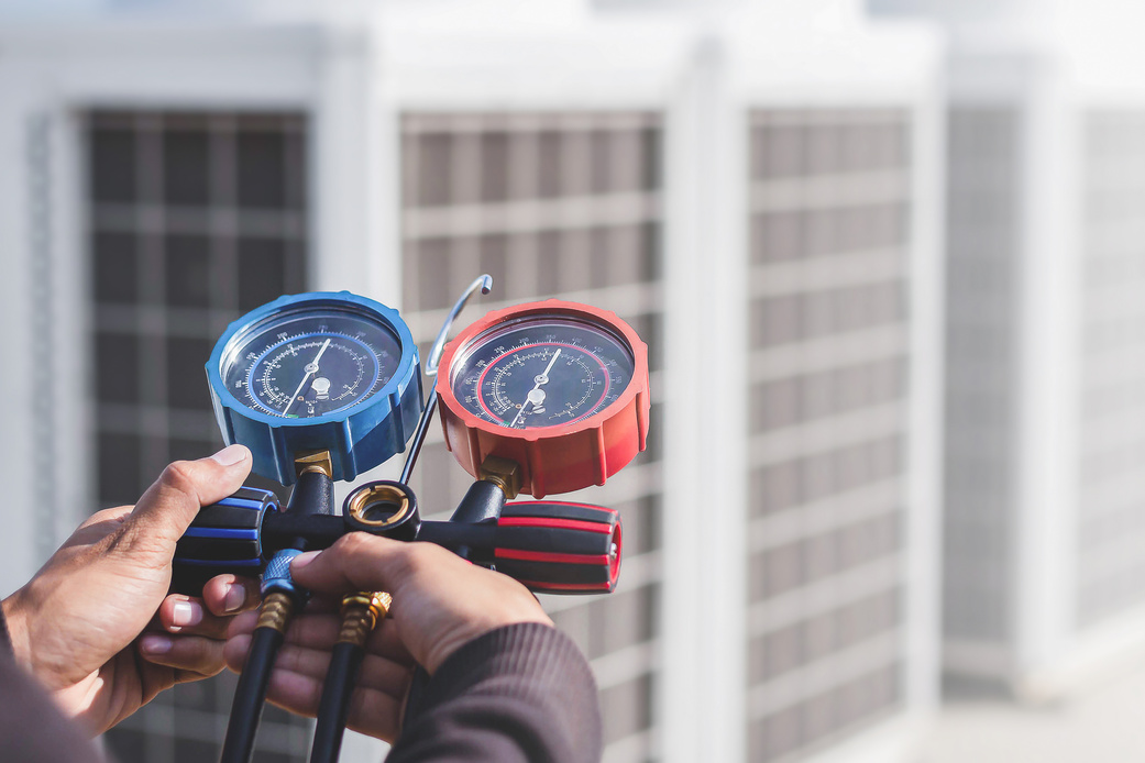 Air conditioning, HVAC service technician using gauges to check refrigerant and add refrigerant.